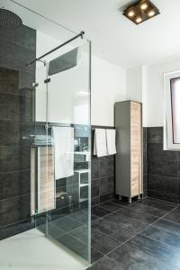 菲根Apartment Griass di Fügen的浴室设有玻璃淋浴间,铺有黑色瓷砖