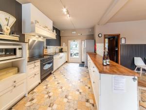 GouvyBeautiful group house with large garden的一间设有白色橱柜和瓷砖地板的大厨房