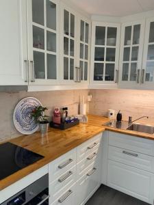斯塔韦恩Koselig maritim leilighet sentralt i Stavern的厨房配有白色橱柜和木制台面
