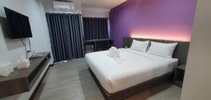 乌汶ทริปเปอร์ โฮเทล的一间卧室设有一张大床和紫色的墙壁