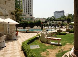 新德里皇家广场酒店的一个带游泳池和椅子的庭院和一座建筑