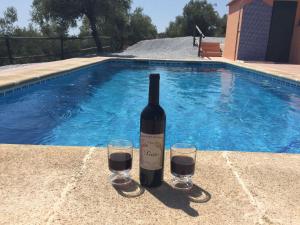 ÁrchezBelvilla by OYO Casa Guzm n的游泳池旁的一瓶葡萄酒和两杯酒