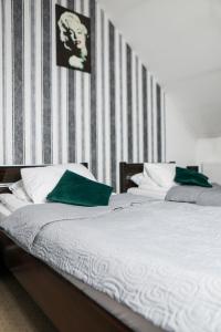 KościelecHotel Złotogórski的卧室内的两张带绿色枕头的床