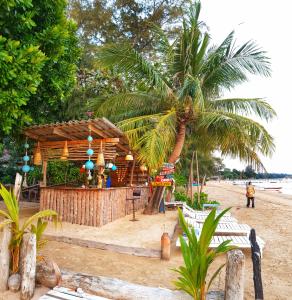 麦岛Sabai Beach Resort的海滩上的木酒吧,种植了棕榈树