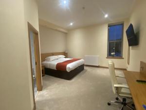 邓弗姆林城市酒店的一间卧室配有一张床、一张书桌和一个窗户。