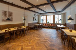 拜尔恩格里斯Schattenhofer Braugasthof的餐厅设有木桌、椅子和窗户。