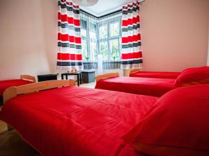 别尔斯克-比亚拉为你旅舍的客房设有两张带红色床单的床和窗户。