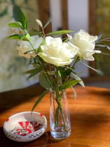 奥托佩尼Hotel Casa Romaneasca的碗旁的花瓶里装有白色玫瑰花