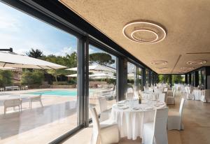 CoriAntico Borgo Molino 7cento vicino ai Giardini di Ninfa的一间带白色桌椅的餐厅和一个游泳池
