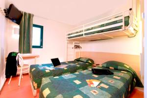 洛翁普拉日敦刻尔克龙海滩普瑞米尔经典酒店的一间卧室配有两张床和一张带笔记本电脑的双层床。