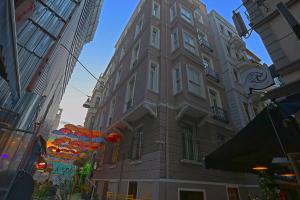 伊斯坦布尔Kamil Bey Suites Hotel的一座高大的建筑,前面有橘子伞