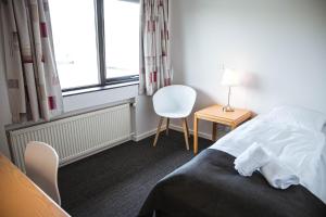 RunevigHotel Runavík的卧室配有床、椅子和窗户。
