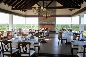 特拉玛斯阿拉佩Altos del Arapey All Inclusive, Golf & Spa的用餐室设有桌椅和窗户。
