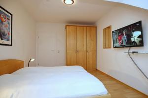 博尔滕哈根Sünnslag Wohnung 148的卧室配有白色的床和墙上的电视。