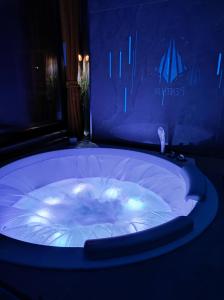 斯科普里PentLux - SPA Penthouse in the heart of Skopje的蓝色灯光客房内的大型按摩浴缸