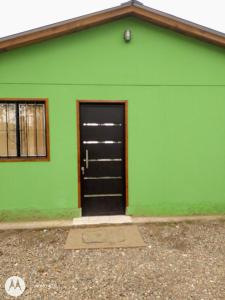 Colonia Las RosasHospedaje El TaTa的绿色建筑,上面有黑色的门