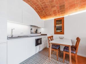 VulpellachBelvilla by OYO Masmore petit Vulpellac的厨房配有白色橱柜和桌椅