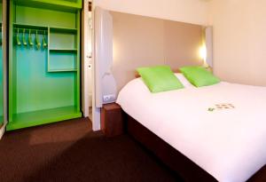 梅斯Campanile Metz Est Technopole - Restaurant的卧室配有带绿色枕头的大型白色床