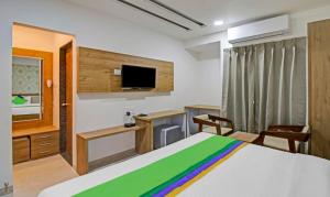 那格浦尔Treebo Trend Chandraprasth Residency的一间卧室配有一张床、一张书桌和一台电视。