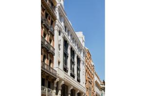 马德里60 Balconies Iconic的大街上一座高大的白色建筑,窗户