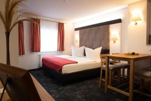 芬特斯沃德Hotel zur Kulturweberei的酒店客房配有一张床铺和一张桌子。