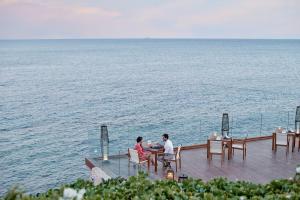 沙姆沙伊赫沙姆沙伊赫四季度假酒店的两人坐在甲板上的桌子上,俯瞰大海