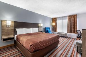 热萨尔弗斯普林斯Quality Inn & Suites Sulphur Springs的酒店客房带一张大床和一把椅子