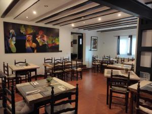 梅迪纳塞利Hotel Rural La Cerámica的餐厅设有桌椅,墙上挂有绘画作品