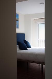 塞维利亚Noches en Triana的窗户间内的一张带蓝色枕头的床