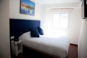 塞维利亚Noches en Triana的卧室配有白色的床、蓝色的墙壁和窗户。