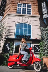 哥本哈根Bryggen Guldsmeden的坐在一辆红色小轮摩托车上,坐在房子前面的女人
