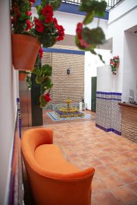 塞维利亚Noches en Triana的鲜花盛开的房间中间的橙色椅子