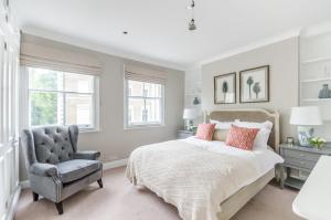 伦敦JOIVY Elegant 2-bed, 2 bath flat with private terrace in South Kensington, close to tube的一间卧室配有一张床和一把椅子