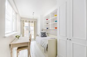 伦敦JOIVY Elegant 2-bed, 2 bath flat with private terrace in South Kensington, close to tube的一间卧室配有一张床、一张桌子和一张桌子