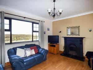 米尔敦马尔贝Flynn's Cottage的客厅配有蓝色真皮沙发和壁炉
