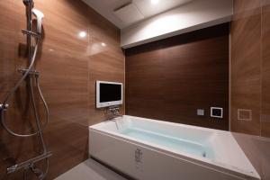 八王子市hotel brattostay ホテル ブラットステイ的带浴缸的浴室和墙上的电视