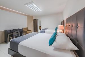 蒙特雷Ayenda Suites Ejecutivas Monterrey的一间卧室配有两张床和一张书桌
