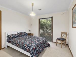托基Holyhead Spa on Whites Beach的一间卧室设有一张床、一个窗口和一把椅子