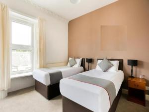 卡诺斯蒂Corner Hotel的一间卧室设有两张床和窗户。