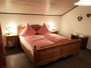 菲利普斯罗伊特Ferienwohnung - Haus Monika的一间卧室配有一张带粉红色枕头的木床。