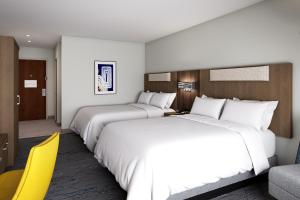 奥马哈Holiday Inn Express & Suites Central Omaha, an IHG Hotel的两张位于酒店客房的床,配有黄色椅子