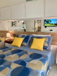 瓜鲁雅Guarujá La Plage Pitangueiras的一间卧室配有蓝色和黄色枕头的床