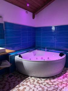 巴罗尼西Setteabbracci Suite & Apartments的浴室设有蓝色瓷砖和大浴缸。