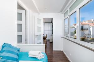 埃斯托利尔Tilias Apartment at Estoril的白色的客房设有蓝色的沙发和大窗户