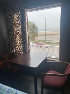 加尔维斯敦冲浪汽车旅馆和公寓的桌椅和享有海滩景致的窗户。