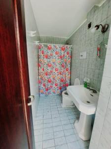 萨尔塔COYA HOSTEL的浴室设有卫生间和带浴帘的盥洗盆。