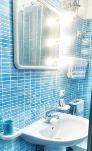 那不勒斯Vima's home的蓝色瓷砖浴室设有水槽和镜子