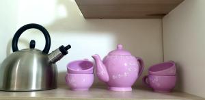 那不勒斯Vima's home的一组粉红色的花瓶和杯子放在架子上