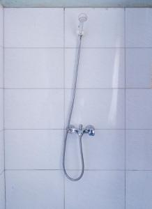坎帕拉Etana Motel Kampala的白色瓷砖墙上的带软管的淋浴