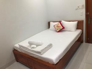 胡志明市Khách sạn Huy Phương的一张带白色床单和毛巾的床